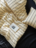 Beige striped blanket with a tag on a dark surface