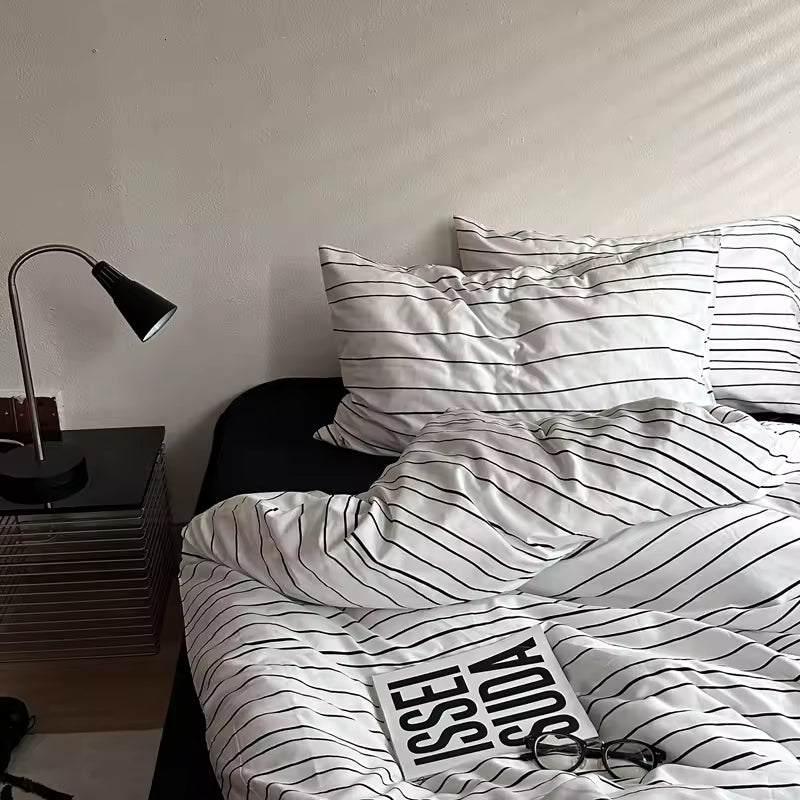 Bed with striped bedding and a lamp on a nightstand in a bedroom.