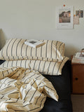 Bed with striped bedding and pillows in a bedroom setting.