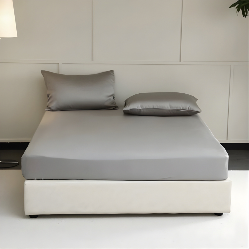 Gray mattress cover with pillows on a bed in a minimalistic room.