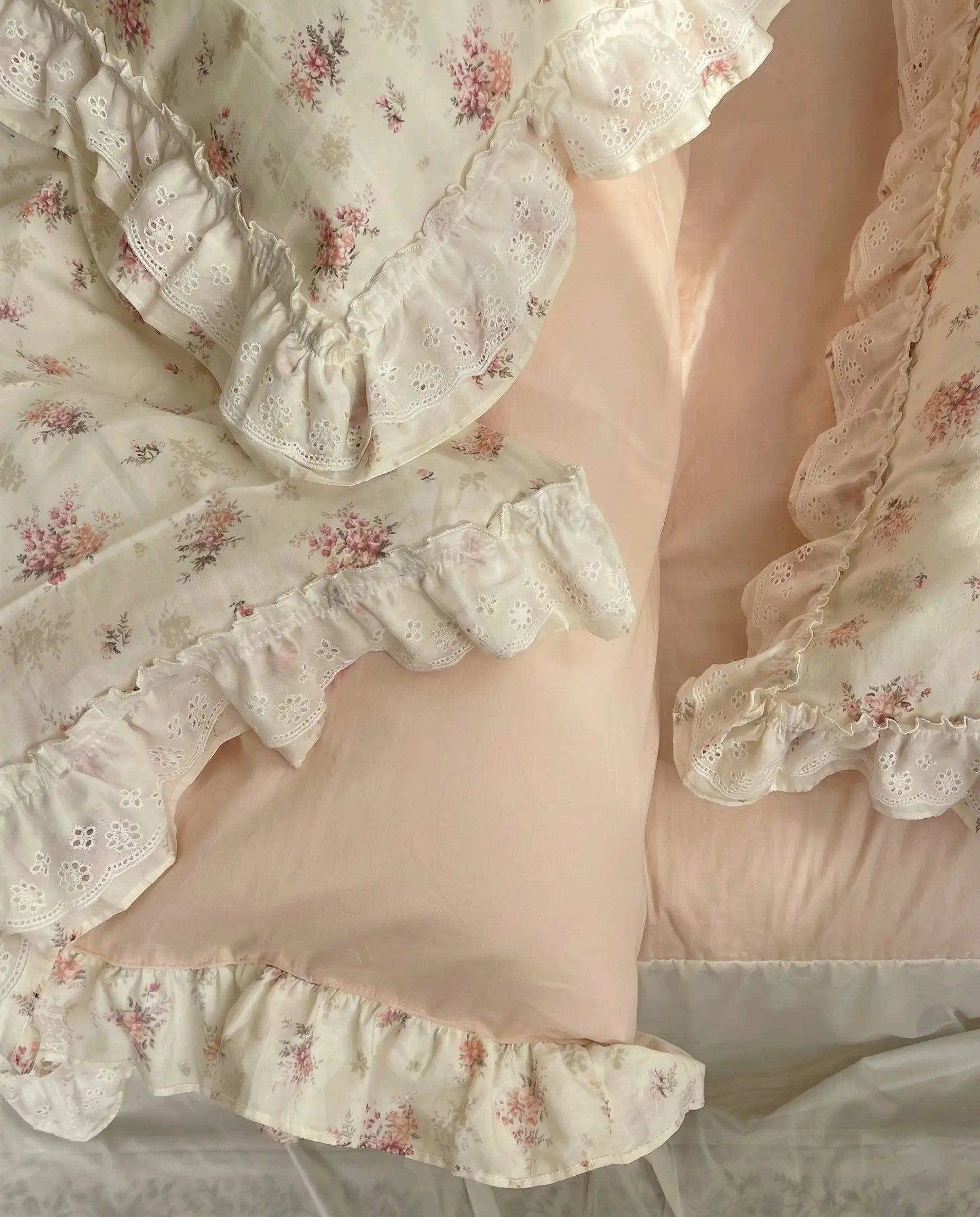Floral-patterned fabric with ruffled edges on a soft pink background