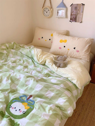 Bed with green and white checkered blanket, decorative pillows, and a teddy bear.