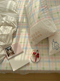 Pastel checkered bedspread with a notebook and small plate on a bed