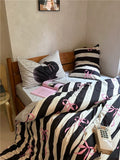 Bed with black and white striped bedding featuring pink bows, in a room setting.