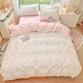 Floral bedding set on a bed in a bedroom with pink and white color scheme.