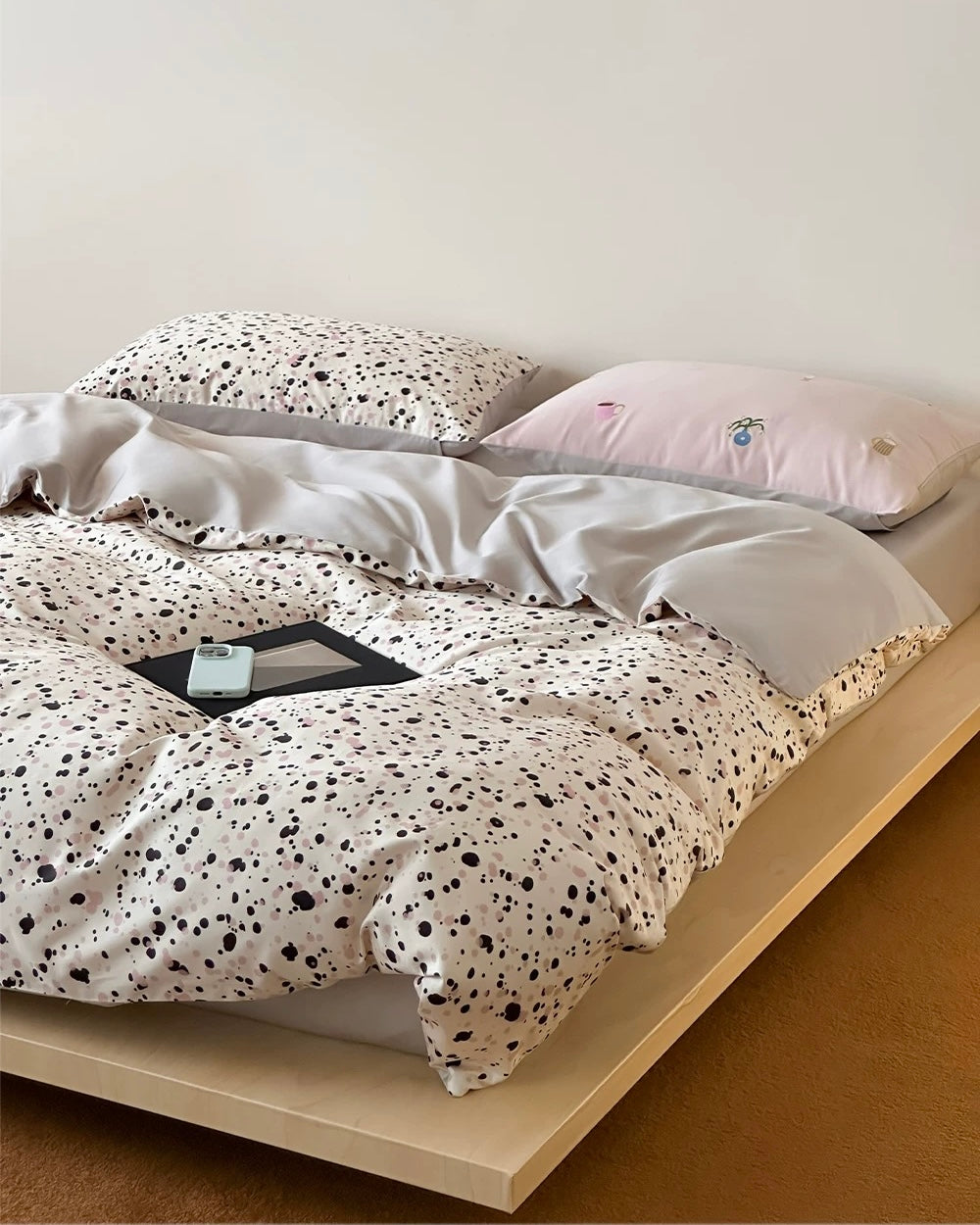 Bed with spotted duvet and pillows on a plain background