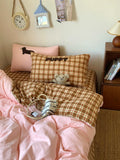 Bed with pink and plaid bedding, pillows with 'Puppy' text, and a teddy bear toy.
