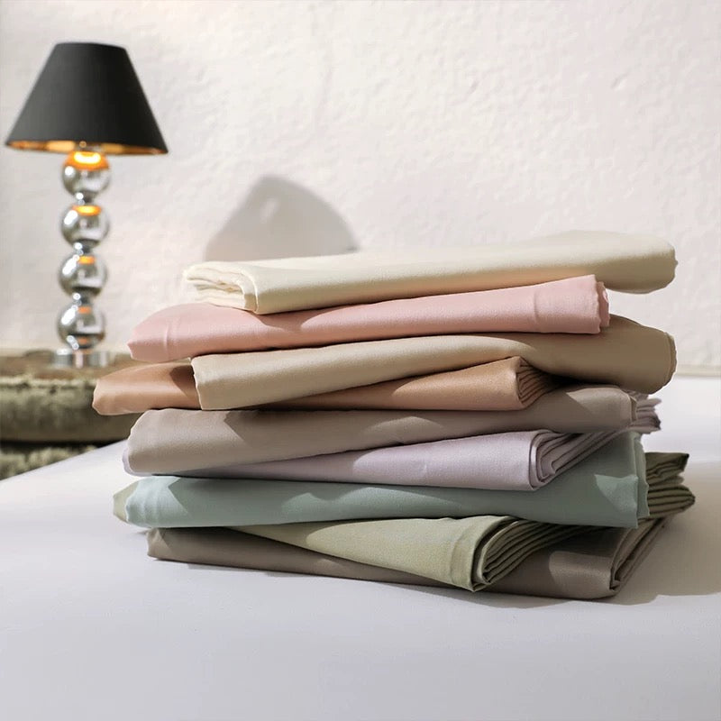 Stack of folded pastel-colored bed sheets on a white surface.