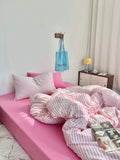 Pink bed with striped bedding in a room setting