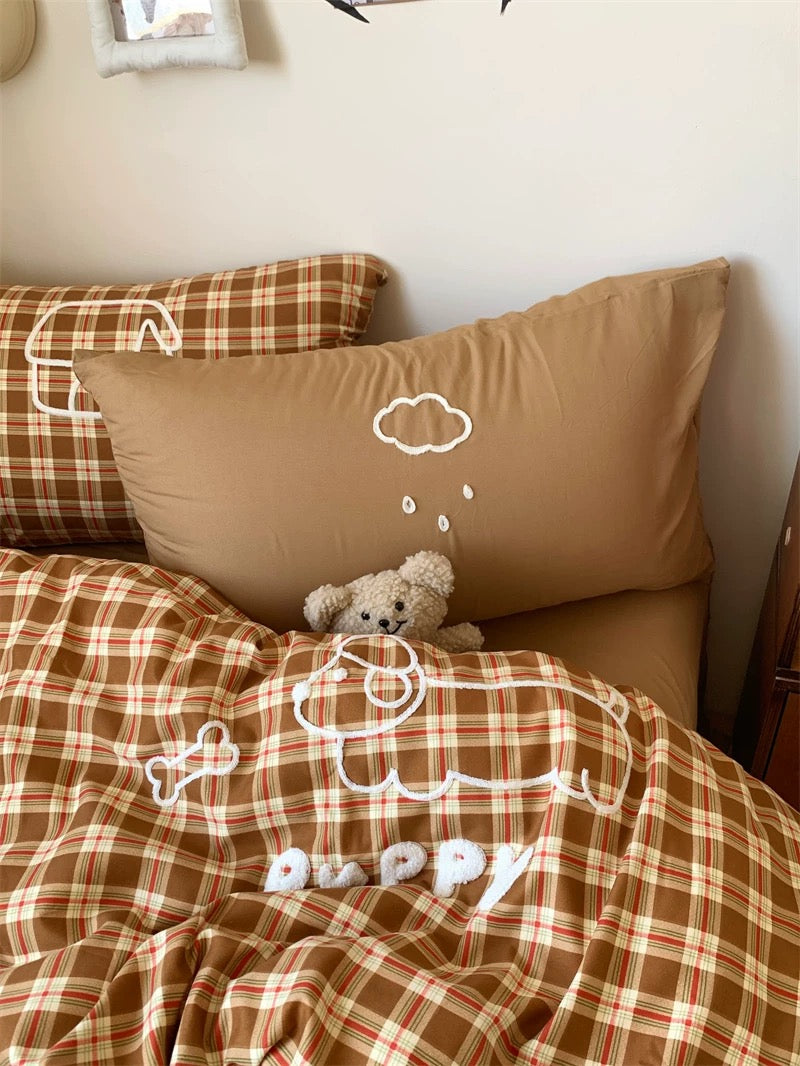 Brown checkered bedding with teddy bear and cloud design on pillows