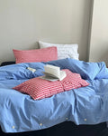 Cotton bedding set in blue with red plaid pillows on low bed