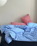 Minimalist bedding setup with blue cotton duvet and red plaid pillows