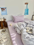 Bedroom with a bed, pillows, and books on a nightstand.