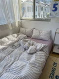 Bedroom with a bed covered in striped bedding, pillows, and a calendar on the wall.