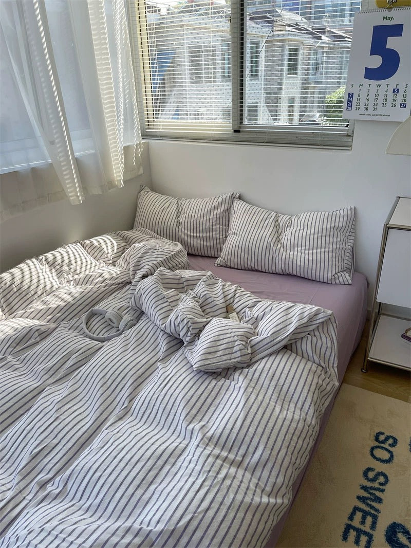 Bedroom with a bed covered in striped bedding, pillows, and a calendar on the wall.