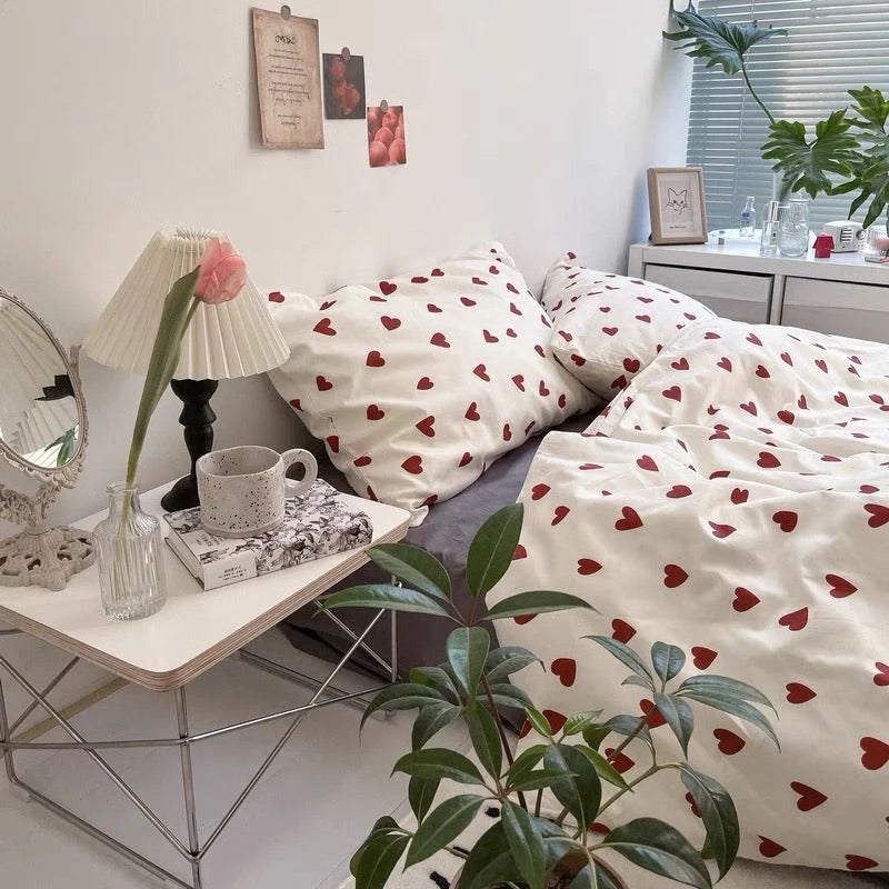 Room interior with heart-patterned bedding, a lamp, and a plant.