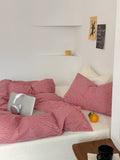 Bed with red striped bedding and a laptop on a white bed frame.