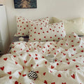 Bed with white bedding and red heart patterns, pillows, and a small black and white checkered pillow.