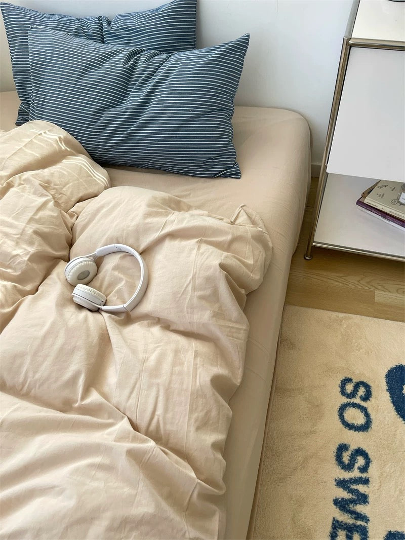 Beige comforter on a bed with blue pillows, nightstand, and decorative items.