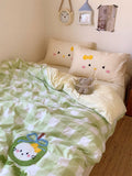Bed with green and white checkered blanket, decorative pillows, and a teddy bear.