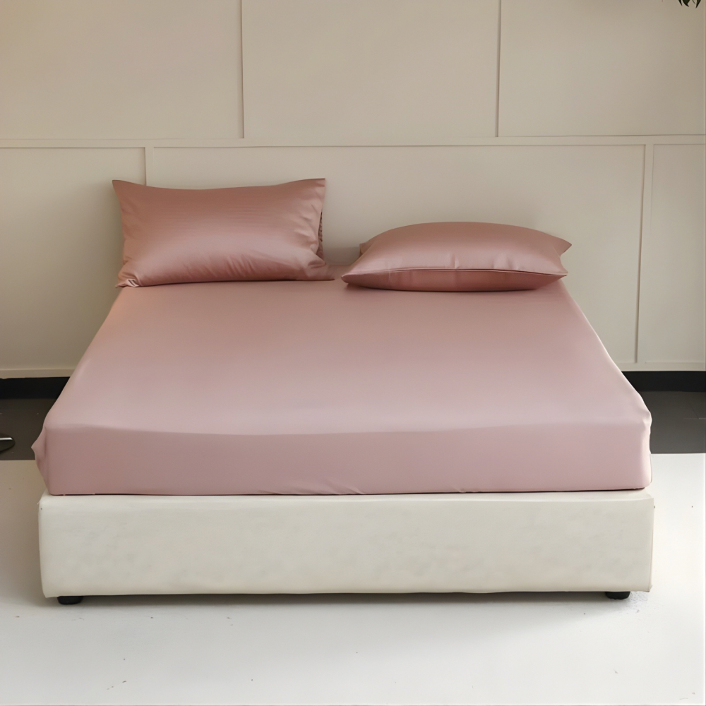 Pink bedspread and pillows on a bed against a beige wall.