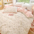 Floral patterned bedding set on a bed with a pink pillow and book.