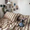 Striped blanket on a sofa with a vase and flowers, surrounded by wall art.