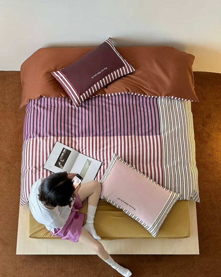 Person sitting on a bed with striped bedding and books, viewed from above.