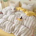 Striped bedding with cartoon dog appliqués and yellow checkered pillows in a bedroom setting.