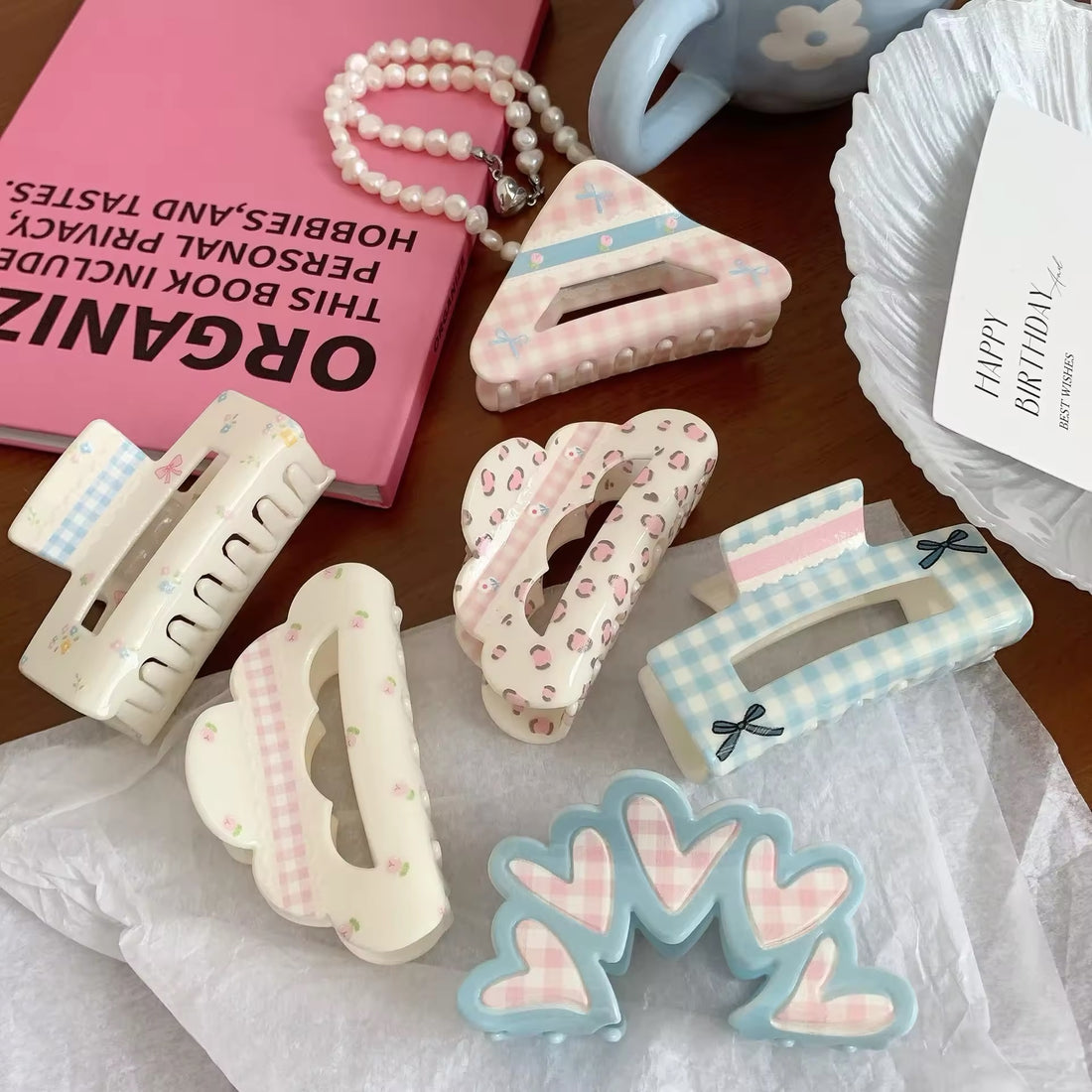 Five coquette-style hair claws laid out on a ceramic plate in a color-coordinated flat lay
