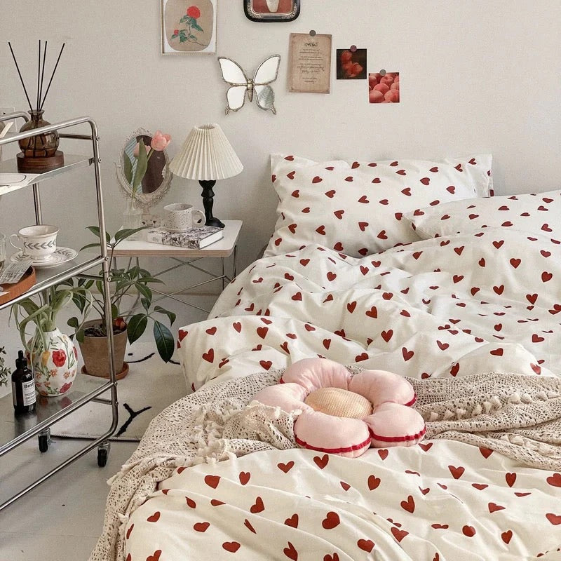 Heart-patterned bedding set on a bed in a bedroom with decorative elements.