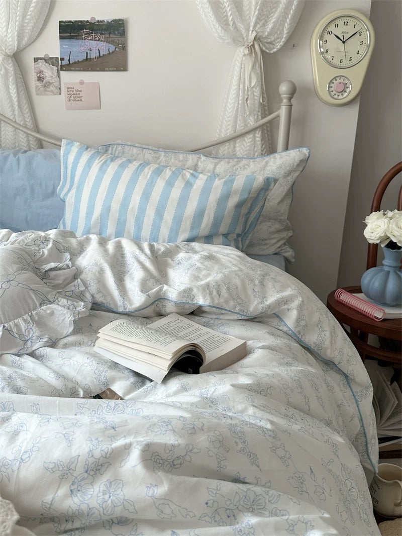 Bedroom with striped pillows and a book on a bed, clock on the wall.