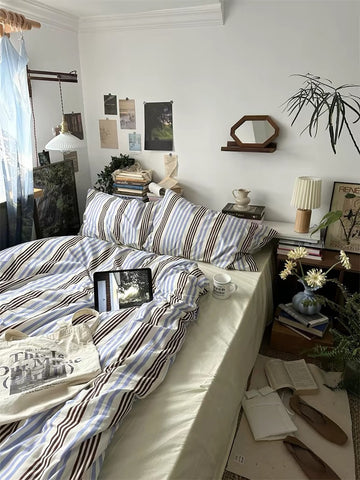 Cozy bedroom with striped bedding, laptop, and decor items.