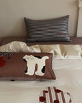 Striped pillow and pillowcase with a cartoon cat design on a bed.