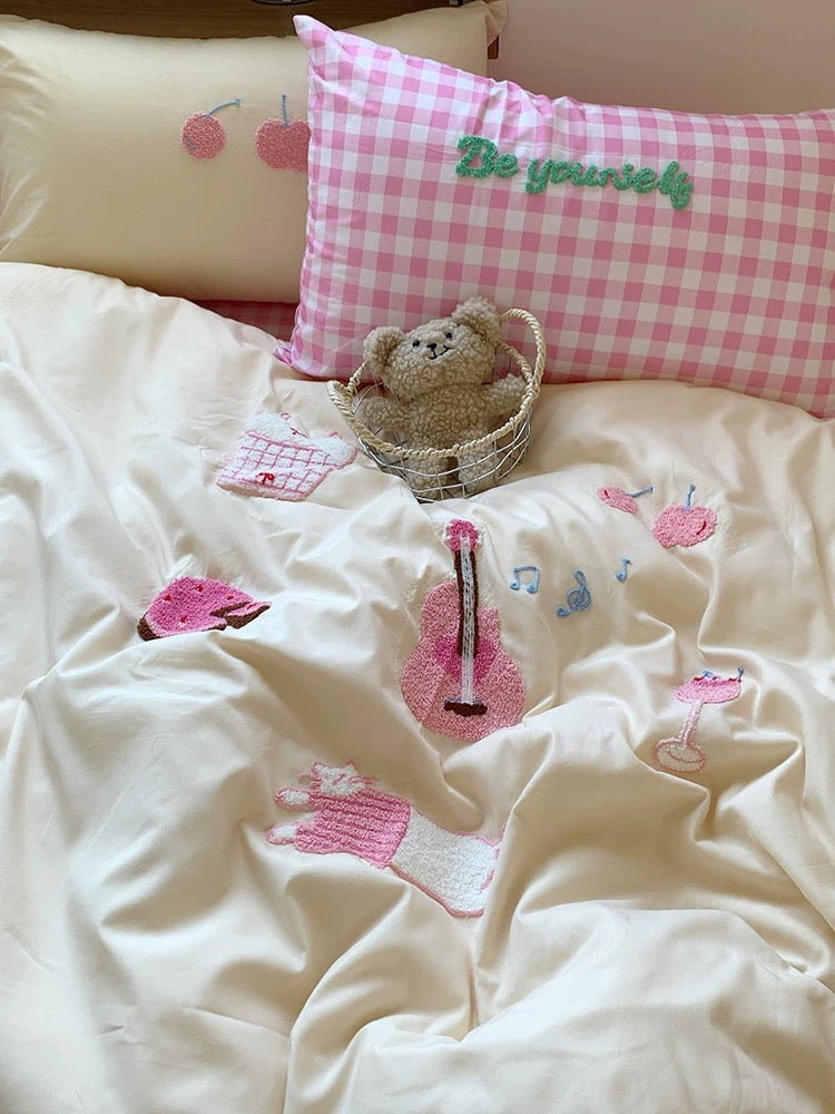 Children's bedroom with pink checkered pillow, teddy bear, and decorative elements on a white bedspread.