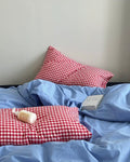 Simple college room bed styled with blue cotton bedding and red checks
