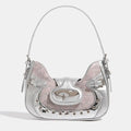 Y2K crescent-shaped shoulder and crossbody bag in silvery pink with crocodile texture, punk-inspired details and metal rivets for edgy 2000s fashion outfits