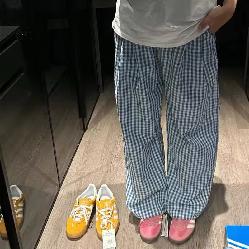 Woman wearing oversized plaid pants with elastic waistband, styled with yellow sneakers and a white tee
