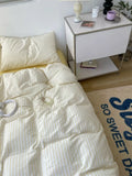 Bed with white comforter and pillows next to a nightstand with decorative items.